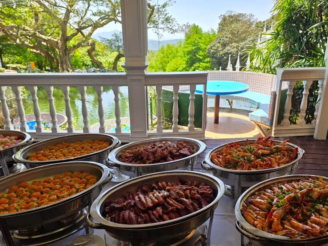 湖畔 Buffet 真愛桃花源湖畔 Buffet 熱食區,保溫餐盤盛裝多道主菜,露台外可見庭園水景與陽明山景