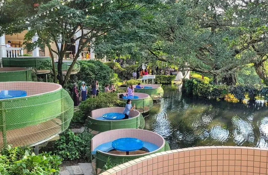 真愛桃花源園區戲水設施與遊客休憩區，綠色滑道旁是水池與樹蔭座位