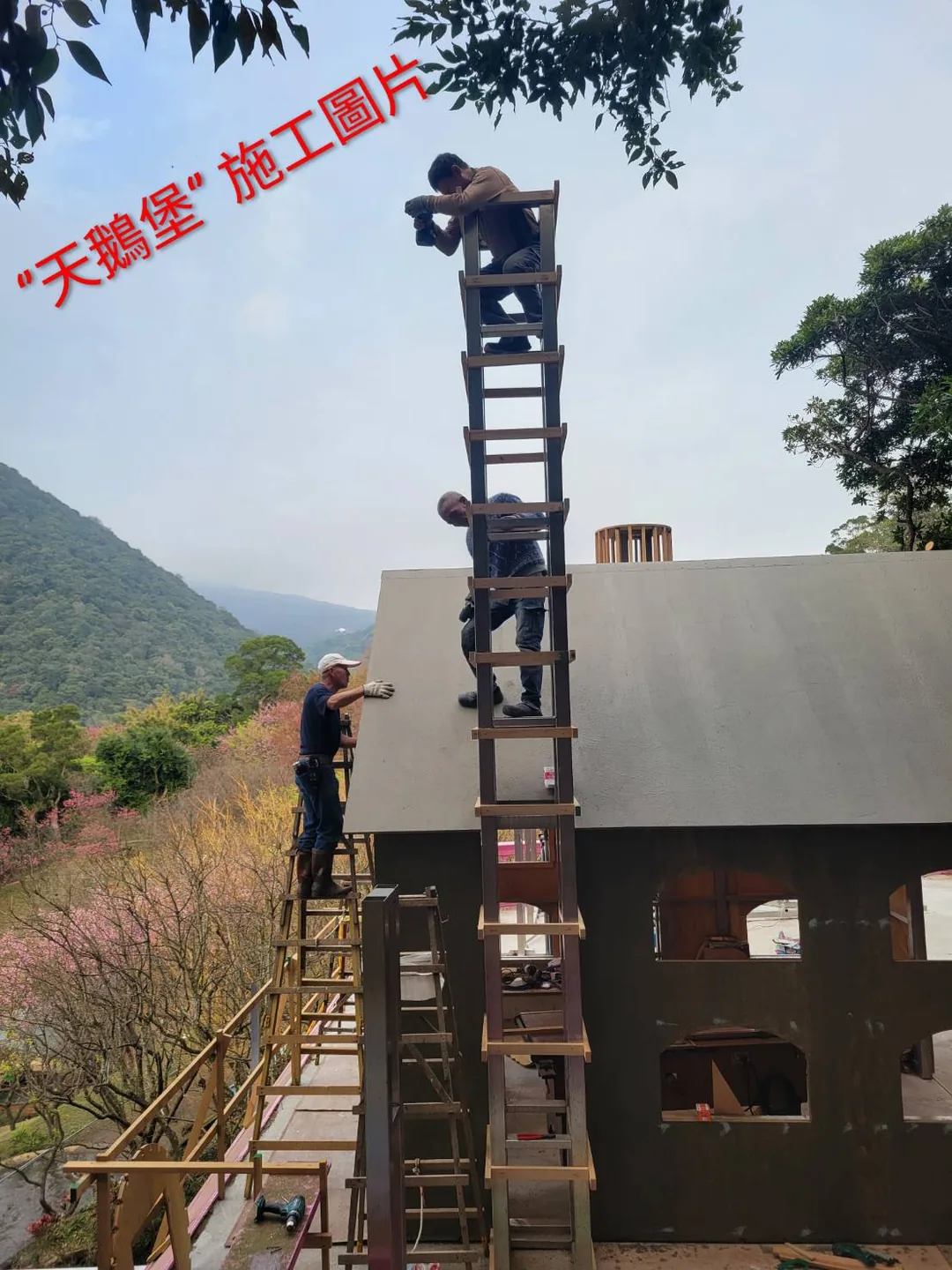 天鵝堡施工現場：師傅站在數層樓高的鷹架上組裝尖塔骨架，背後是陽明山山景