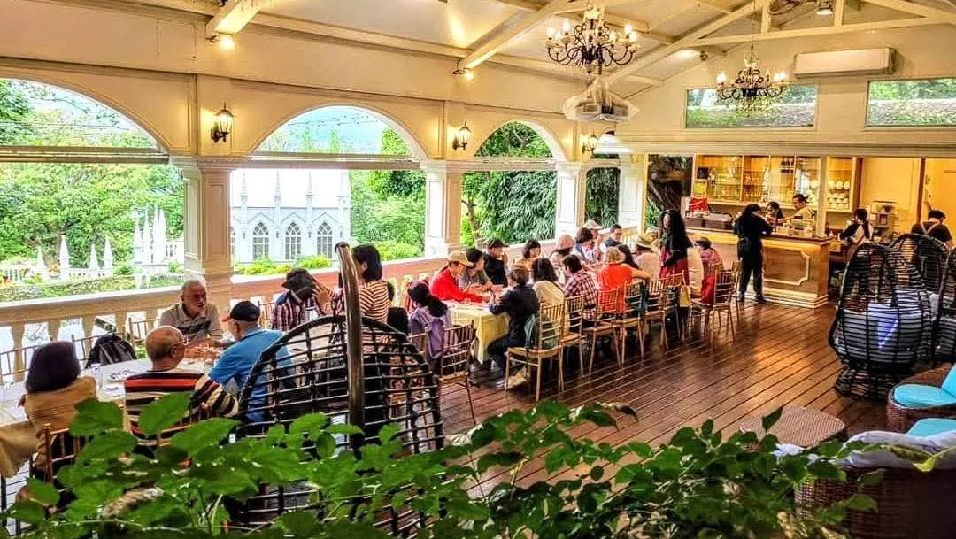 真愛桃花源庭園餐廳露台用餐區，拱形廊柱外可見哥德式教堂與陽明山山景，長桌聚餐座無虛席